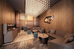 A modern lounge area with a curved sofa, round coffee table, and a bar with seating. - Crystal Orange (Shanghai Oriental Pearl Binjiang) (Shanghai)