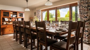 Un comedor con una mesa de madera dispuesta para seis personas, rodeada de sillas, un aparador de madera y una lámpara colgante arriba.