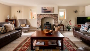 Una sala de estar acogedora con chimenea, sofás de cuero, una mesa de centro y una estantería.