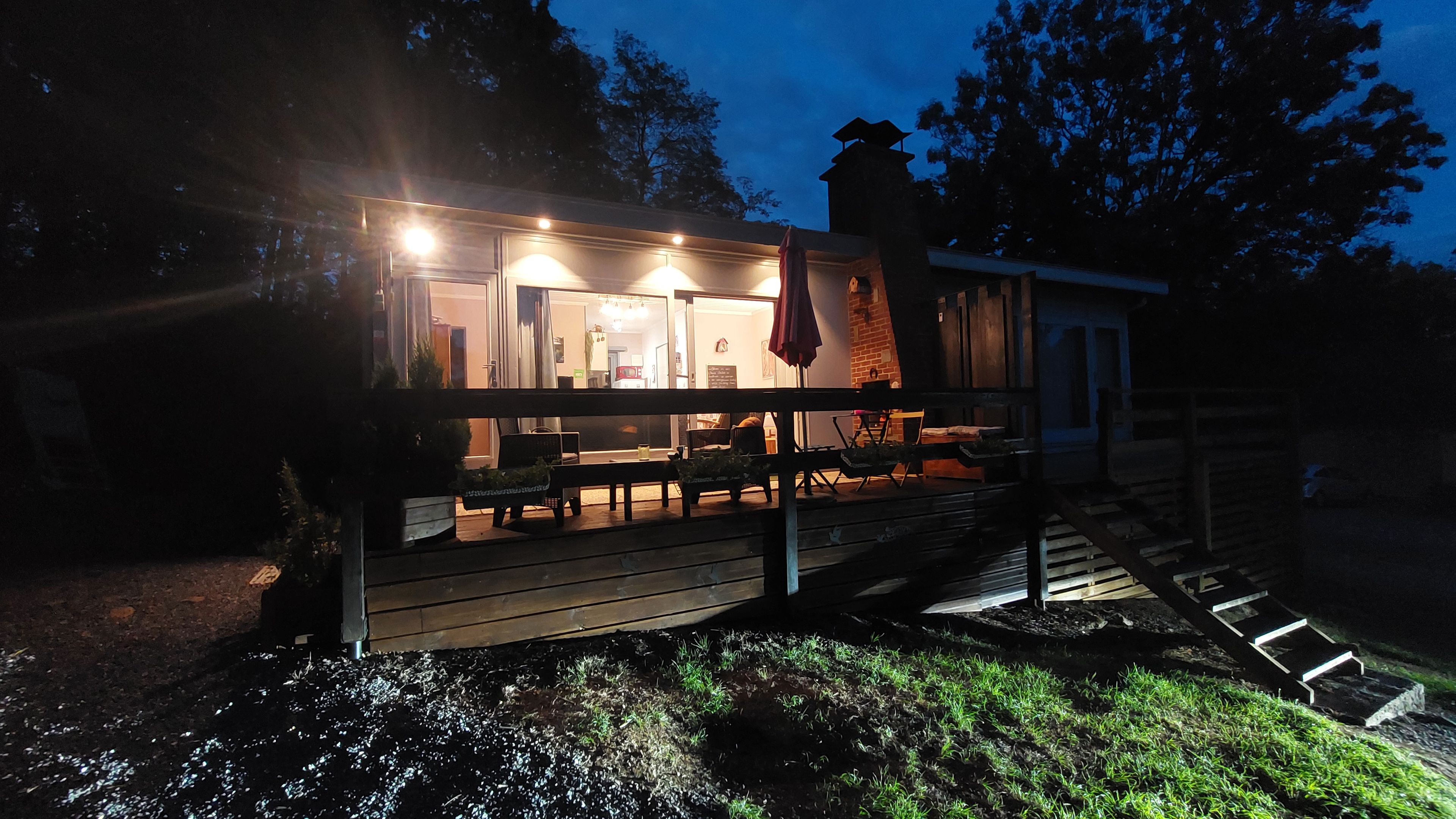 Een houten terras met buitenmeubelen en een trap naar een gebouw.