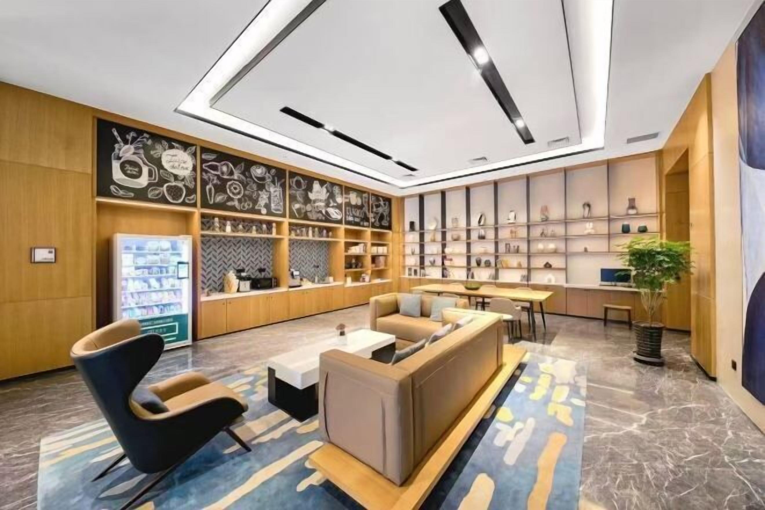 Un hall d’entrée moderne avec un canapé, des fauteuils, une machine à café et un présentoir à chaussures.