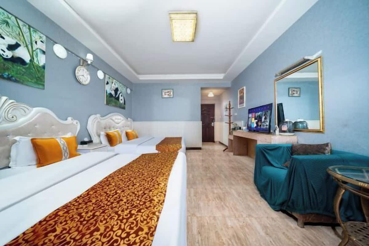 A hotel room with a large bed, a sofa, a dining area, and a mirror.