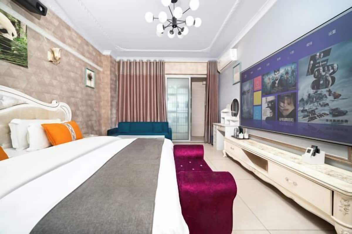 A hotel room with a bed, a TV, a dresser, and a door leading to a balcony.