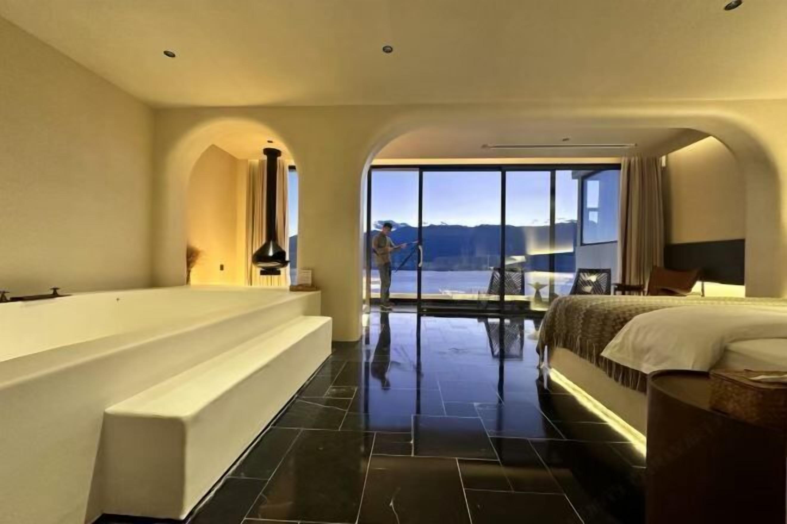 Une chambre d’hôtel moderne dotée d’une grande baignoire, d’un lit et offrant une vue sur les montagnes.