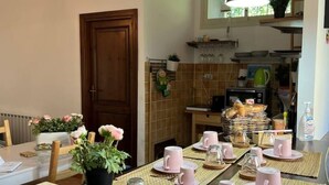 A dining area with a table set for a meal, a potted plant, and kitchenware on the counter.