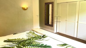 A modern bedroom with a large bed, a wall-mounted light, a mirror, and a sliding door closet.