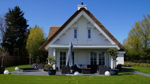 A two-story house with a steep gabled roof, a covered porch, and a well-maintained lawn.