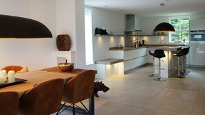 A modern kitchen with a central island, bar stools, and a dining area with a table set for four.