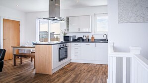 Una cocina moderna con armarios blancos, una isla central y un horno empotrado.