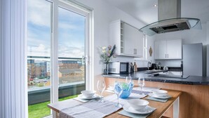 Una cocina moderna con armarios blancos, un microondas integrado y una campana extractora con puerta de vidrio.