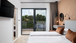 A modern hotel room with a large bed, a TV, a desk with a chair, and a balcony with a table and chairs. - Luxury Villa David 2 heated pool 38m2 bbq Seaview (Podstrana)