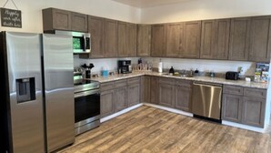 A modern kitchen with wooden cabinets, stainless steel appliances, and a wooden floor. - Spacious family friendly 4-BR property with AC, Fireplace and WiFi in Sutton, WV (Sutton)