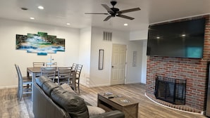 A living room with a sofa, coffee table, TV, fireplace, and a dining area with chairs and a table. - Spacious family friendly 4-BR property with AC, Fireplace and WiFi in Sutton, WV (Sutton)