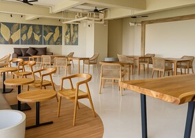 A modern meeting room with wooden tables and chairs, a ceiling fan, and a large wall mural.
