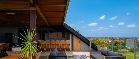 Un patio al aire libre con zona de comedor, asientos y vistas a la ciudad.
