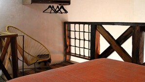 A bedroom with a bed, a yellow chair, and a window with a wooden frame.