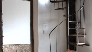 A room with a spiral staircase, a stone wall, and a wooden floor.