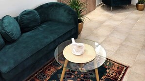 A modern living room with a green sofa, a glass coffee table, and a decorative wall panel. - B&B Il Salento di Fioravante (Minervino di Lecce)