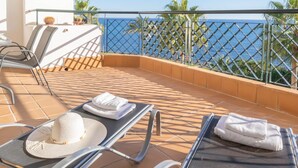 A balcony with two sun loungers, a table, and chairs. - Mi Capricho Beach Front sea View Pool (Mijas)