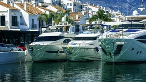 A marina with yachts docked, white buildings with red-tiled roofs, and mountains in the background. - Villa Zacaluca Pool Whirlpool Sauna Gym (Marbella)