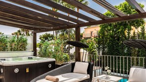 A covered outdoor seating area with wicker furniture, a hot tub, and a pool in the background. - Villa Zacaluca Pool Whirlpool Sauna Gym (Marbella)