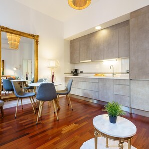 A modern kitchen with grey cabinets, a white countertop, and a round marble table with a potted plant. - M Laga Center Old Town (Málaga)