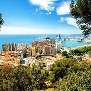 A coastal cityscape with a prominent bullring, high-rise buildings, and a marina. - M Laga Center Old Town (Málaga)
