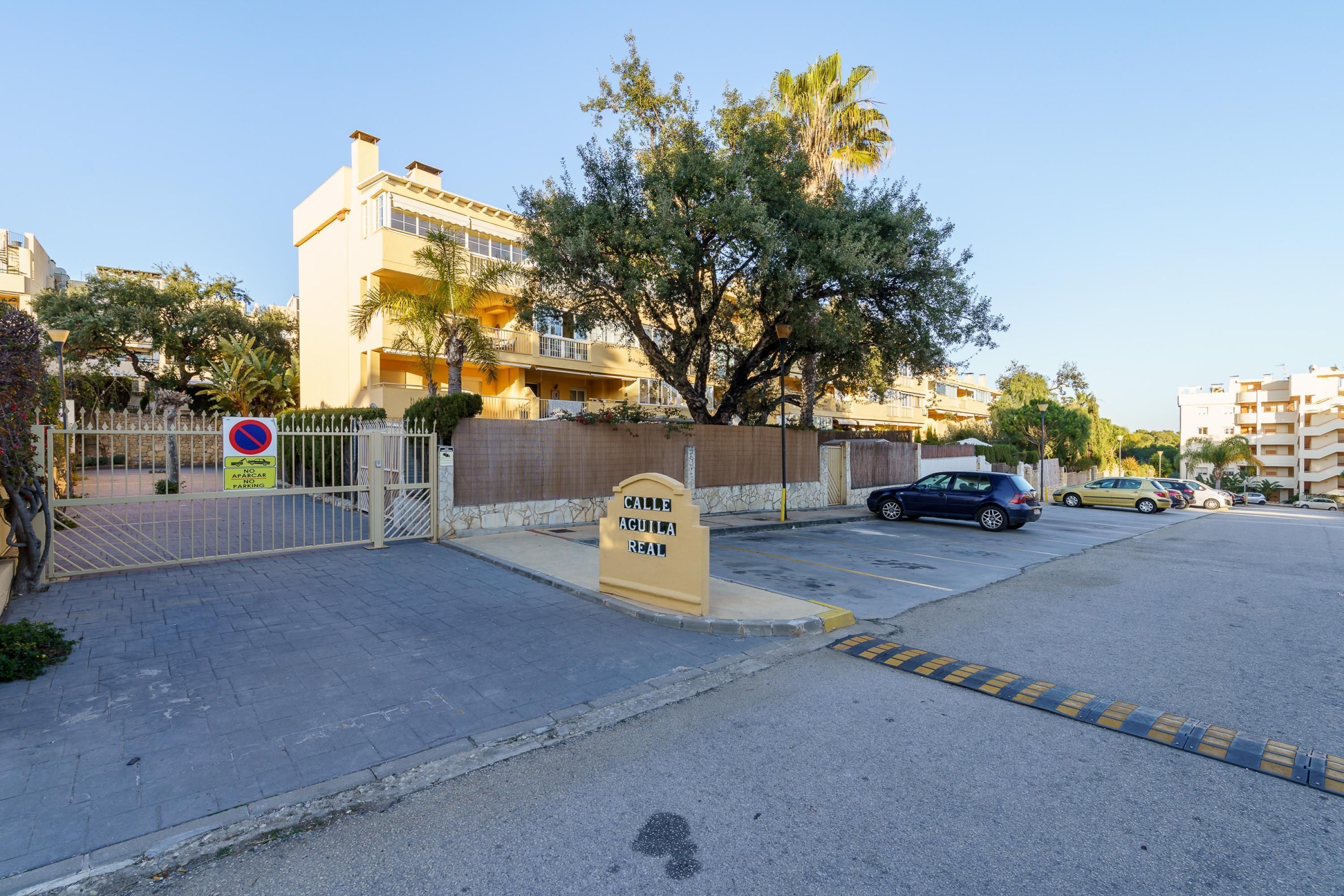 Una entrada porticada a un edificio residencial, con un letrero que indica 'Calle Aguila Real'.
