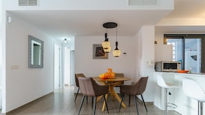 A modern kitchen with a dining area, featuring a round table with chairs, a hanging light fixture, and a microwave on the counter. - Apartment La Cala With Pool (Mijas)