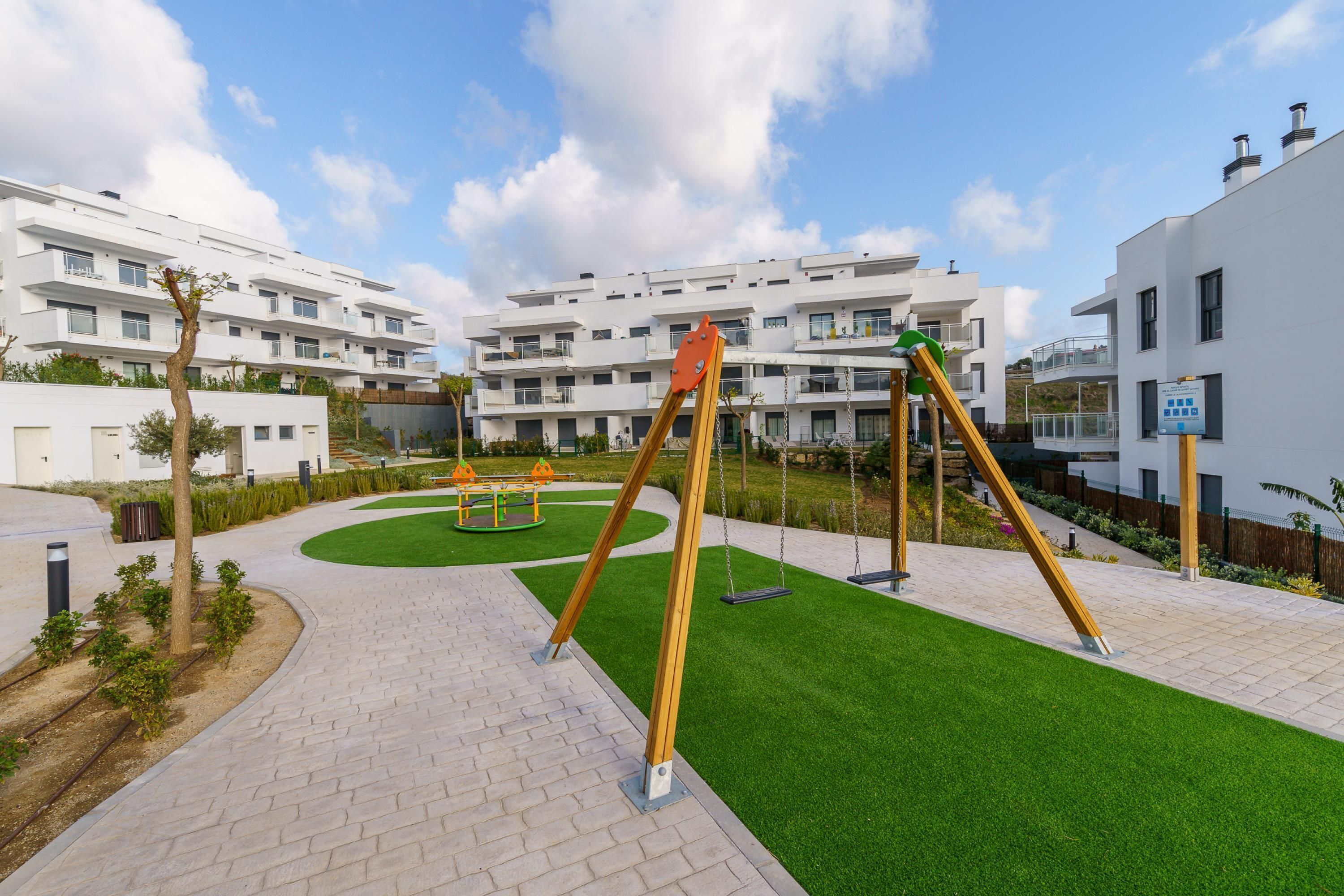 A modern residential area with a playground featuring swings and a seesaw.