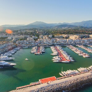 An aerial view of a marina with numerous boats docked in a grid pattern, surrounded by residential buildings and mountains in the background. - Seaview Sunny Altos De Calahonda Pool (Mijas)