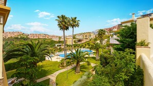 Et resort med swimmingpool, palmer og udsigt over det omkringliggende boligområde.