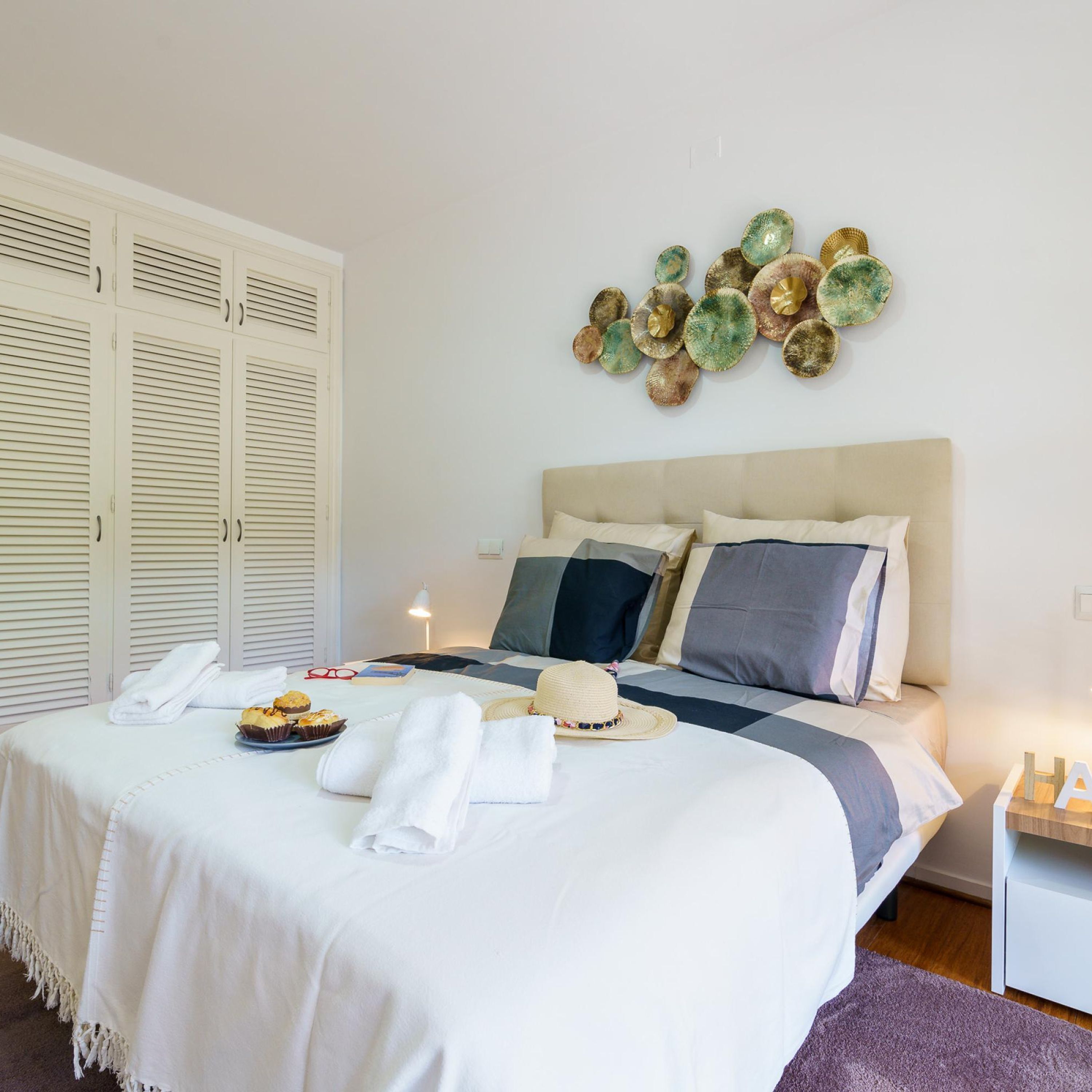 A neatly made bed with a white duvet, pillows, and a bedside table with a lamp.