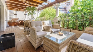 An outdoor patio with wicker furniture, a glass table, and a view of the city. - Duplex Marbella Concordia Close To Beach (Marbella)