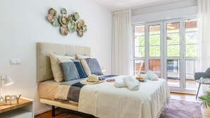A modern bedroom with a bed, bedside table, and a view of the outdoors through large windows. - Duplex Marbella Concordia Close To Beach (Marbella)