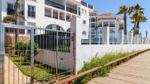 Un hotel moderno con una facciata bianca, numerosi balconi e una passerella in legno.