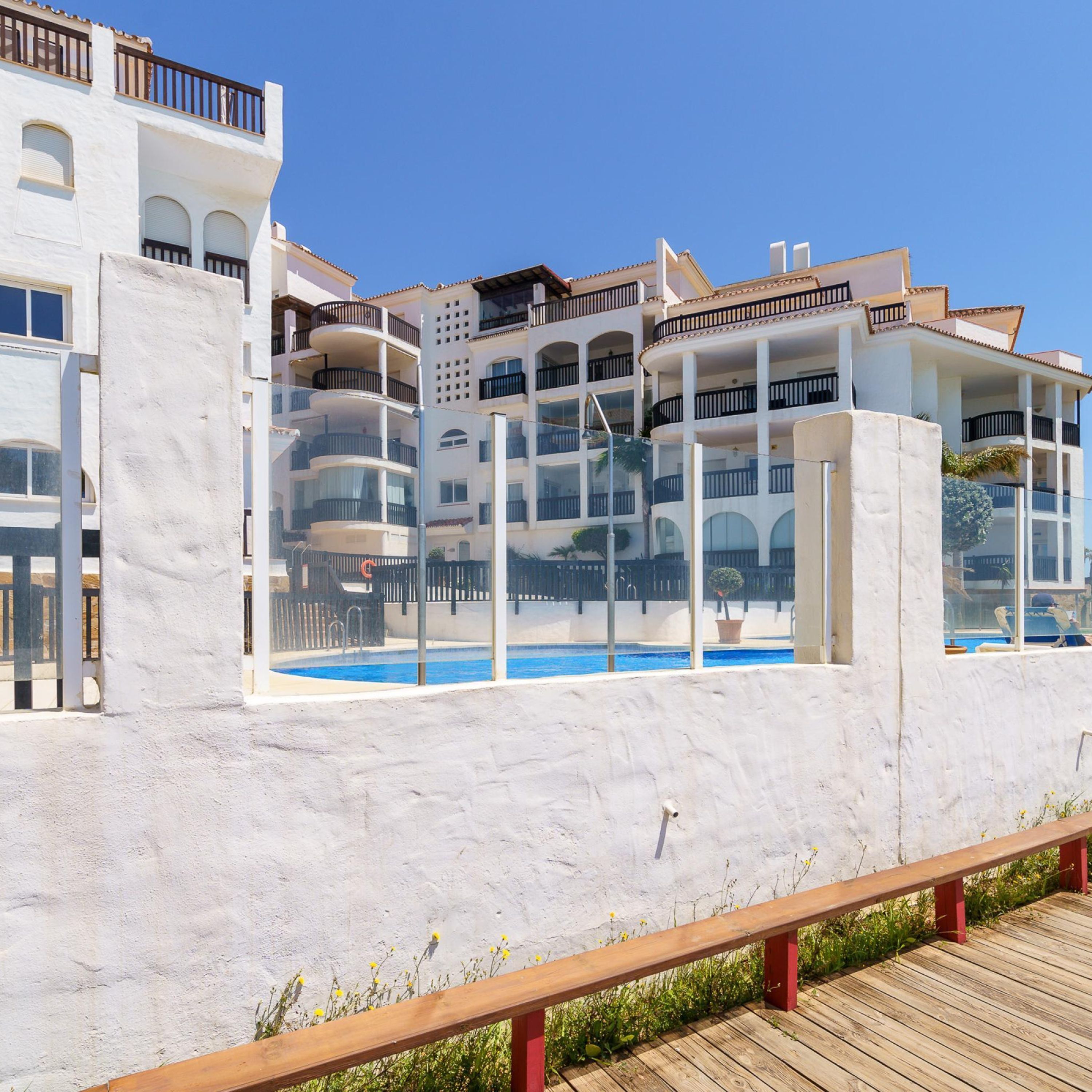 A multi-story hotel with balconies, a swimming pool, and a wooden deck.