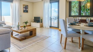 A modern living room with a dining area, large windows, and a view of the sea. - Sunset Seaview Corner With Pool (Estepona)