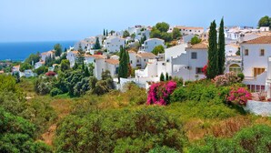Un village côtier aux bâtiments blancs, avec un ciel dégagé et une vue sur la mer.