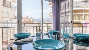 Un espace de salle à manger moderne avec une table en verre, des bols turquoise et des verres à motifs.