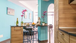 Une cuisine moderne avec des meubles en bois, un petit réfrigérateur et un coin repas comprenant un canapé et des tabourets de bar.