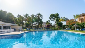 A clear swimming pool with lounge chairs and palm trees in the background. - Marbella Este Next Marriott and Nikki B (Marbella)