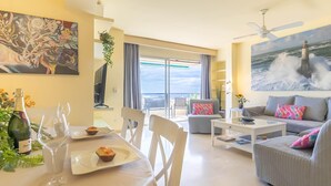 A modern living room with a dining area, a balcony with a view of the sea, and a painting of a lighthouse. - Marbella Este Next Marriott and Nikki B (Marbella)