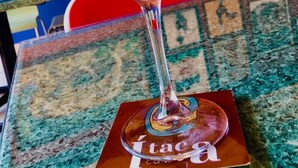 Un cóctel en copa de martini con una rodaja de lima y un posavasos con el texto 'Itaca'.