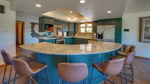 Een moderne keuken met een centraal eiland, barstoelen en ingebouwde apparatuur.