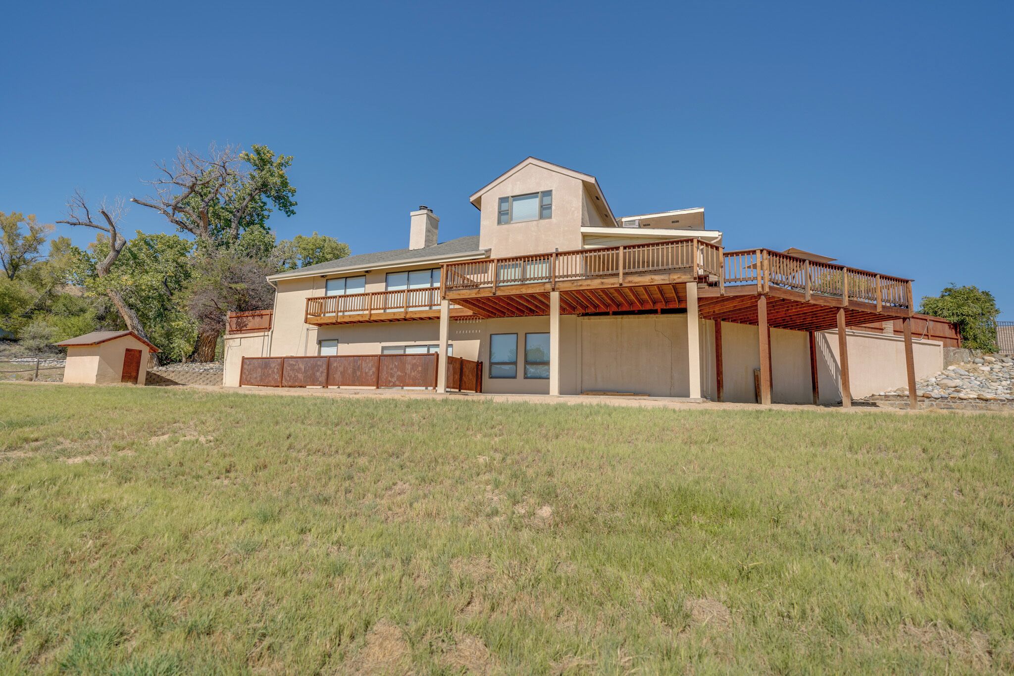 A two-story house with a large deck, a garage, and a small detached garage.