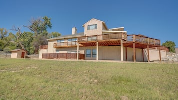 A two-story house with a large deck, a garage, and a small detached garage.