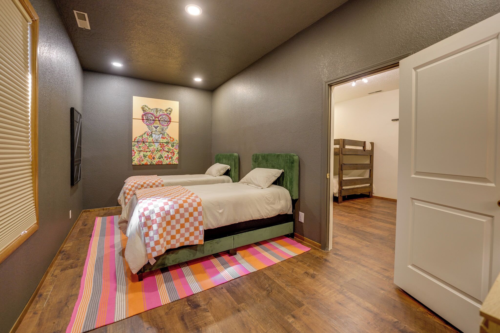 Une chambre avec deux lits, un tapis rayé aux couleurs vives et un tableau accroché au mur.