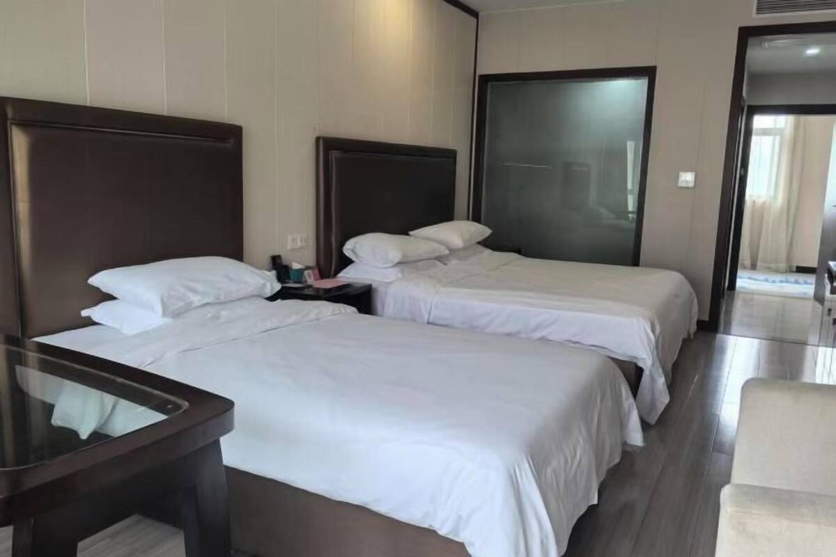 A hotel room with two beds, a desk, and a chair.