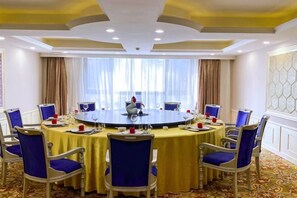 Une salle de conférence avec une table ronde, des chaises bleues et une nappe jaune.